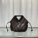 Brown woven handbag on a reflective surface with a neutral background