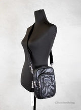 Black crossbody bag on a mannequin against a white background